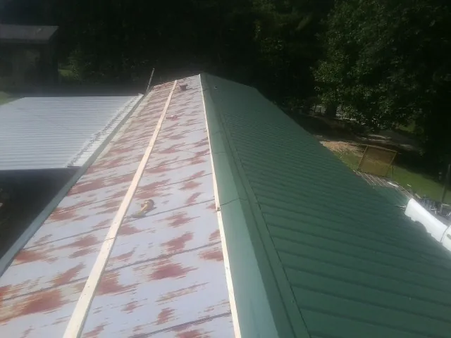 Old rusted panels beside newly installed green metal roofing — Wind Damage Roof Repair by Roofing Brothers in Warm Springs
